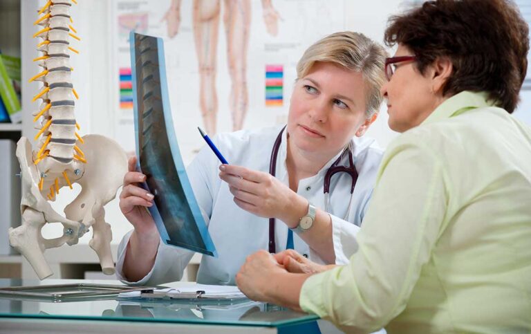 Patient discusses back pain with a chiropractor during a calm, professional examination.