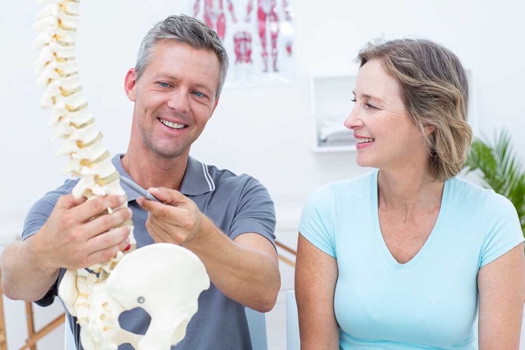 Pregnant woman receiving a gentle, supported back adjustment on her side in a clinical room.